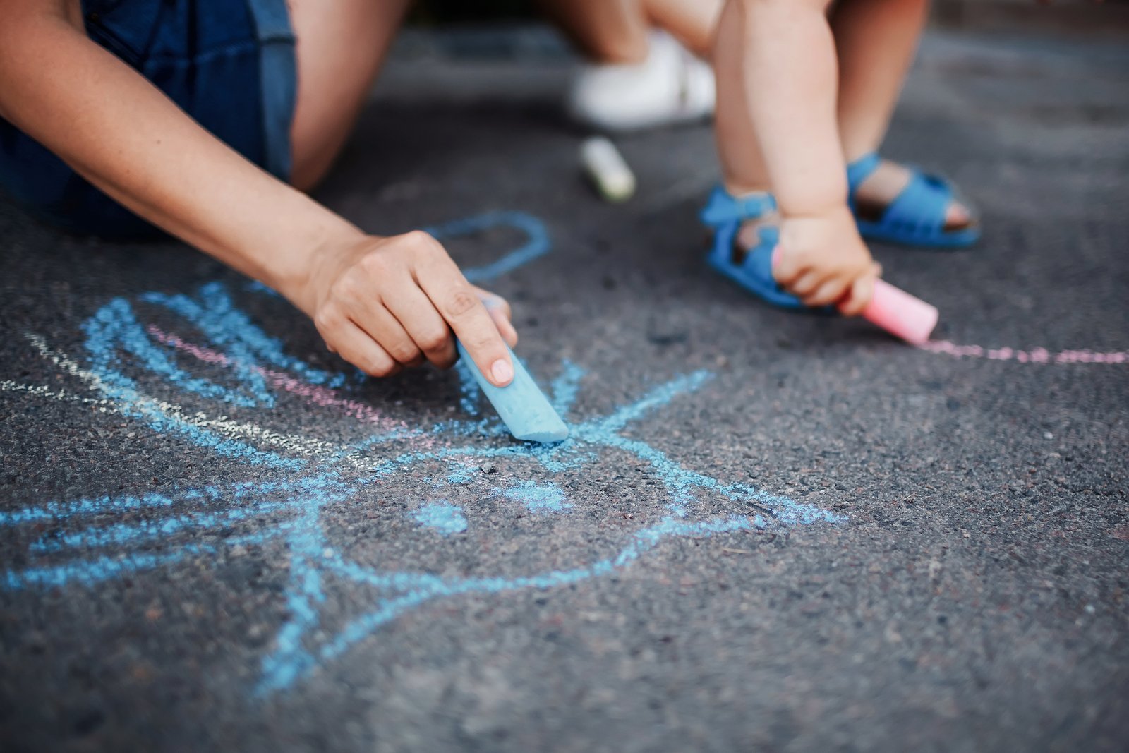 Девочки рисуют мелом на тротуаре